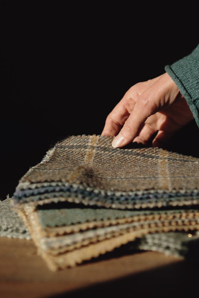 A neat pile of wool fabric samples with a hand holding the top sample